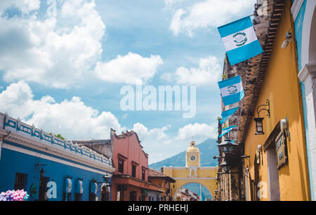 Guatemalan flags fly leading up to the famous yellow arch of Santa Catalina in Antigua Guatemala on a sunny independence day Stock Photo