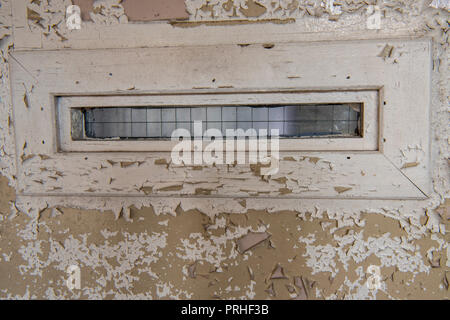 Narrow window on the door of a prison cell with old, peeling paint. Stock Photo