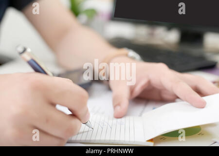 Man is writing work on notepad with pen. Stock Photo