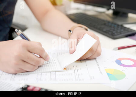 Man is writing work on notepad with pen in hand. Stock Photo