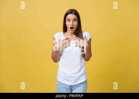 Beautiful female half-length portrait isolated on yellow studio backgroud. The young emotional smiling and surprised woman standing and looking at camera.The human emotions, facial expression concept Stock Photo