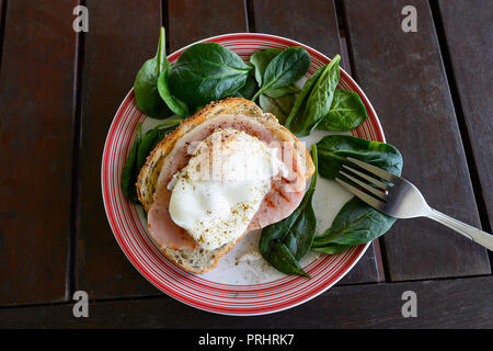 A healthy dish of poached egg served on a plate with spinach salad, bacon rasher and a piece of toast Stock Photo