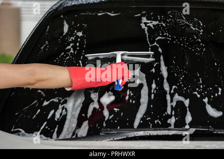 hand using squeegee to washing windshield of a car Stock Photo