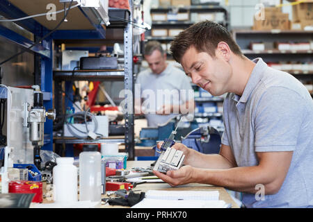 Engineer In Factory Measuring Component At Work Bench Using Micrometer Stock Photo