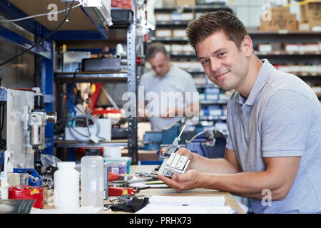 Portrait Of Engineer In Factory Measuring Component At Work Bench Using Micrometer Stock Photo