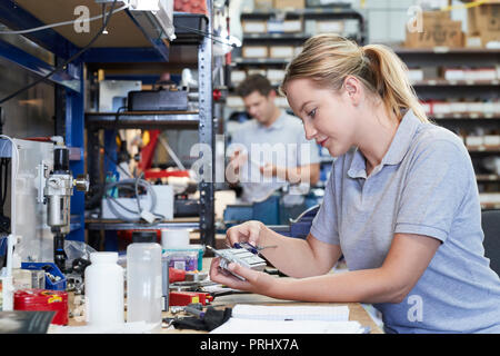 Female Engineer In Factory Measuring Component At Work Bench Using Micrometer Stock Photo