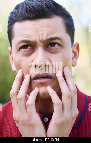 Outdoor Head And Shoulder Portrait Of Worried Young Man Stock Photo
