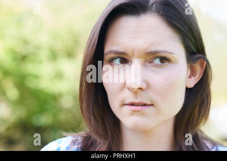 Outdoor Head And Shoulder Portrait Of Worried Young Woman Stock Photo