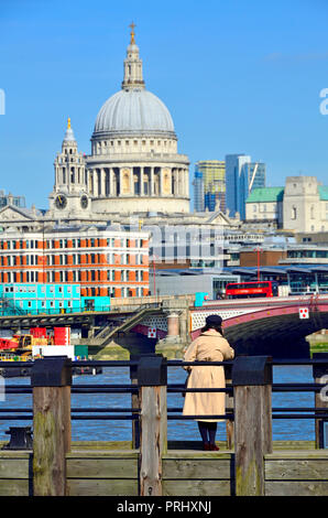 Woman looking towards St Paul's Cathedral from one of the wooden piers on Gabriel's Beach, South Bank, London, England, UK. Stock Photo