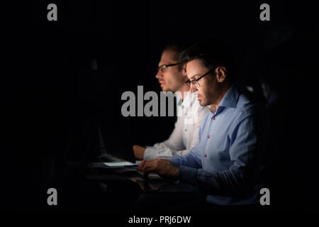two colleagues sitting at the Desk.isolated on black Stock Photo