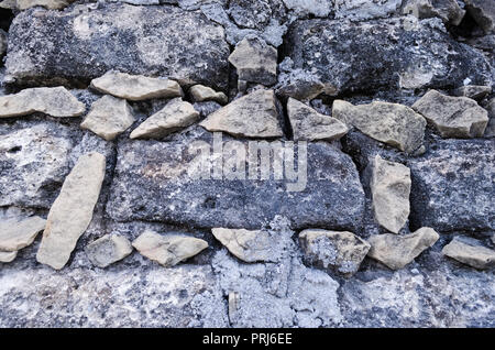 Stone wall, small stones forming square bricks. Ancient wall with broken and rusty stones. Stock Photo