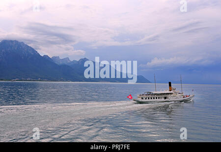 Cruise steamer on Lake Geneva against the background of beautiful mountains and reflection in the water before the storm, Switzerland Stock Photo