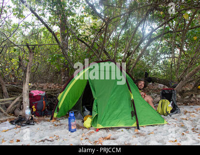 Man sitting near the orange tent on the beach of lake Baikal, Russia Stock Photo