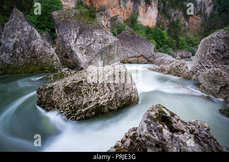 Fast flowing water around huge boulders and river stones in the Gorges du Tarn Aveyron France Stock Photo