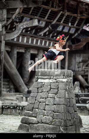 Man in traditional attire stone jumping over rock platform on Nias Island, Sumatra, Indonesia Stock Photo