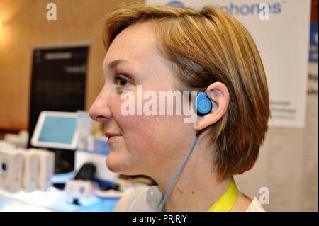Woman demonstrating hearing electronic device at CES (Consumer Electronics Show), the world’s largest technology trade show, held in Las Vegas, USA. Stock Photo