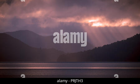 Rays of sun beaming through the clouds over lake waikaremoana, New Zealand Stock Photo