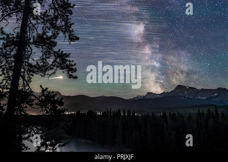 The stars trailing as they move east to west (left to right), ending with the Milky Way and Galactic Centre (right) over Storm Mountain and the Vermil Stock Photo