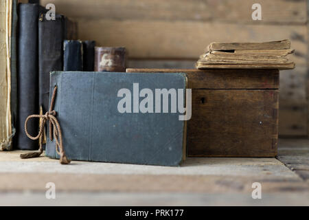 Old books and a wooden box set on a shelf. Old publishing houses set side by side on a wooden table. Dark background. Stock Photo