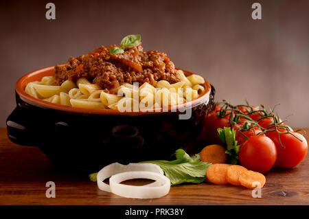 Penne pasta in tomato sauce with chicken, tomatoes decorated with parsley on a wooden table