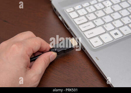 Man is connecting black hdmi cable into laptop. Stock Photo