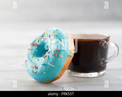 Blue donut and coffee on gray wooden background with copy space. Glazed doughnut and coffee cup on grey wooden table with copyspace Stock Photo