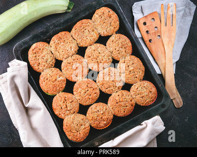 Top view of baking tray with homemade vegetables muffins. Cupkace with zucchini, carrots, apple and cinnamon on black cement background. Sweet vegetables homemade muffins. Toddler-friendly recipe idea Stock Photo