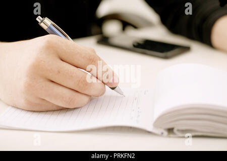 Business man hand with pen writing on notepad. Stock Photo