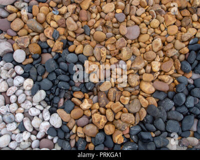 Geology. Sea pebbles on beach, various colors and types of stone. Multicoloured stones - black, white, yellow. Stock Photo