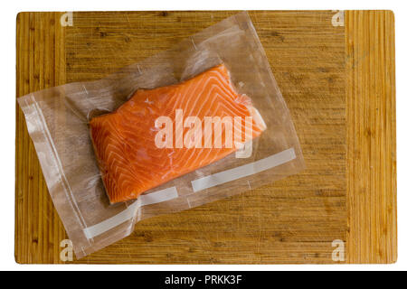 Vacuum packed fresh Atlantic salmon fillet in a transparent plastic bag on a wooden chopping board viewed from above ready for freezing Stock Photo