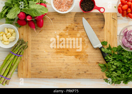 https://l450v.alamy.com/450v/prkp75/overhead-view-of-wooden-cutting-board-surrounded-by-assorted-vegetables-including-onion-and-asparagus-with-knife-prkp75.jpg