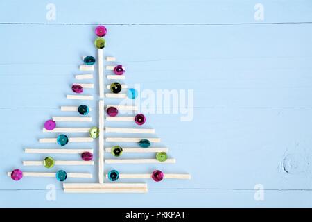 christmas tree of small wooden sticks and shiny sequins. Blue wooden background and copy space Stock Photo