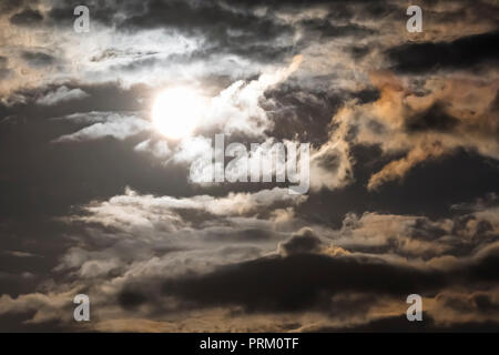Full moon overexposed and very bright against a cloudy, night time moody sky. Stock Photo