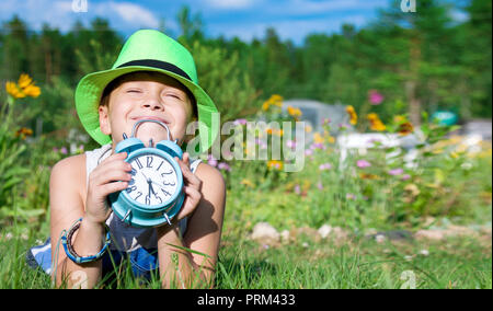 Dreams. Boy in hat laying with alarm clock. Copy space Stock Photo