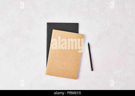 Top view of brown and black notebook with black pencil on rose and white background. Flat lay with copy space. Stock Photo