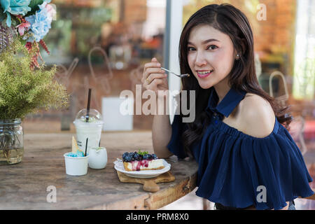 young woman eating blueberry cheese cake at cafe Stock Photo