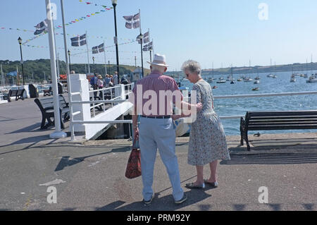 An old, retired couple holding hands  on a pier in Cornwall. Stock Photo