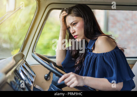 stressed woman sitting inside a vintage car Stock Photo