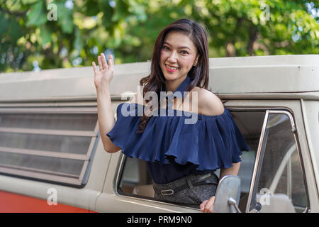 happy woman open window of a vintage car and raising her hand Stock Photo