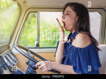 tired young woman driving vintage car and yawning Stock Photo