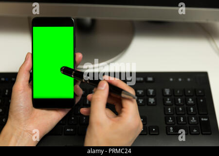 Women's hands touches phone screen with pen for touchscreen. Mobile phone with a green screen. Stock Photo