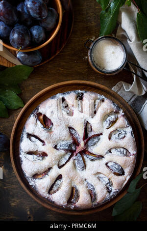 Delicious dessert plum pie, sweet delicious holiday cake with plums on wooden table. Top view flat lay background. Stock Photo