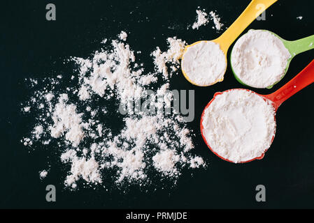 top view of a flour in a colorful measuring cup on black background. concept of cooking,bakery and food ingredient Stock Photo