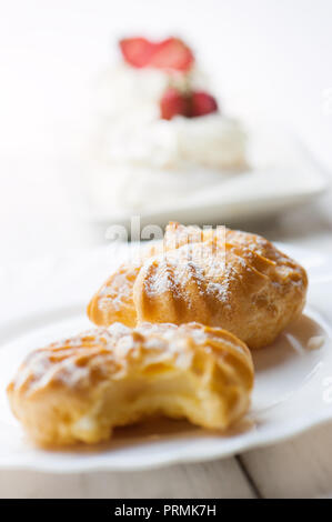 Fresh eclairs with cream on white plate. Stock Photo