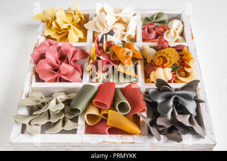 Mixed set of dry multi-colored Italian pasta on a white old wooden box. Background. Close up Stock Photo