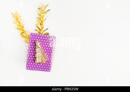 Violet (purple) gift box with christmas symbol tree on it with golden decoration on light background with copy space, flat lay Stock Photo