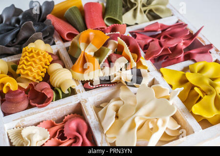 Mixed set of dry multi-colored Italian pasta on a white old wooden box. Background. Close up Stock Photo