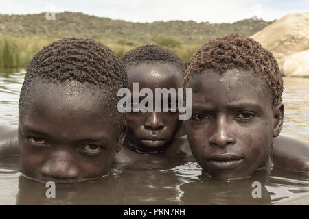 April 25, 2017 - Lake Eyasi, Ngorongoro district, Tanzania - Manu (14), Alagu (12) and Osama (15) are bathing in a natural spring next to their camp.The Hadza are one of the last remaining societies, which remain in the world, that survive purely from hunting and gathering. Very little has changed in the way the Hadza live their lives. But it has become increasingly harder for them to pursue the Hadza way of life. Either the Hadza will find a way to secure their land-rights to have access to unpolluted water springs and wild animals, or the Hadzabe lifestyle will disappear, with the majority o Stock Photo