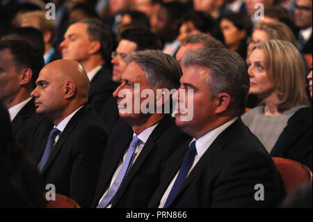Birmingham, England. 3rd October, 2018.  L-R Sajid Javid MP, Secretary of State for the Home Department, Philip Hammond MP, Chancellor of the Exchequer and Brandon Lewis MP, Chairman of the Conservative Party and Minister without Portfolio, listening to the keynote speech of Theresa May MP, Prime Minister and Leader of the Conservative Party, on the closing session of the fourth day of the Conservative Party annual conference at the ICC.  Kevin Hayes/Alamy Live News Stock Photo