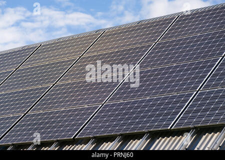 A large row of solar panels on a roof on a sunny day Stock Photo